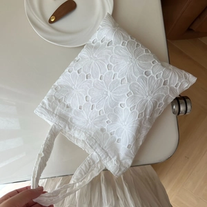 Detail of white cotton tote bag featuring delicate eyelet flower embroidery and textures
