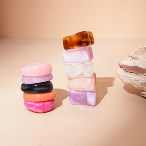 Minimalist acrylic geometric resin ring set with amber and marble textures on stone
