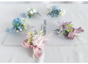 Macro detail of artificial flower boutonnieres in five colors with pearls and silk ribbons