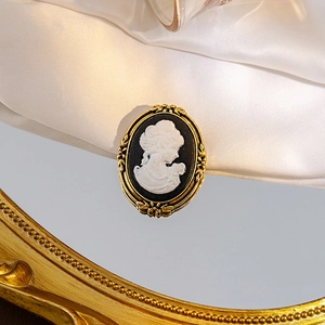 Macro shot of vintage cameo brooch with white portrait on gold-tone frame on silk