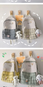 Detail of plaid school backpacks with cute plush pendants and rainbow brand logo