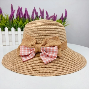 Detail of light brown straw hat featuring a pink plaid bow and burlap decoration
