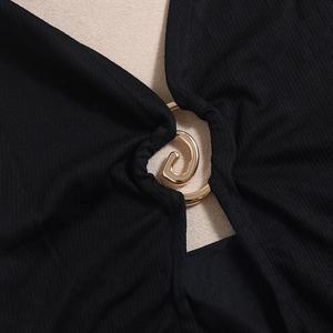 Detailaufnahme einer goldenen Spiralschnalle auf schwarzem Rippstrick-Kleidgewebe