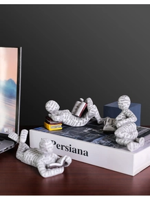 Tre statuine da lettura in resina nordica con scritte nere su scrivania in legno