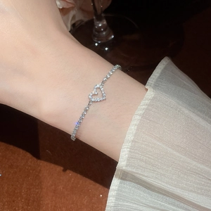 Macro shot of silver heart bracelet with white pavé zircons on woman's wrist