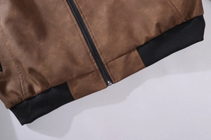 Detail einer braunen Wildlederjacke mit schwarzem Rippbündchen und Metallreißverschluss