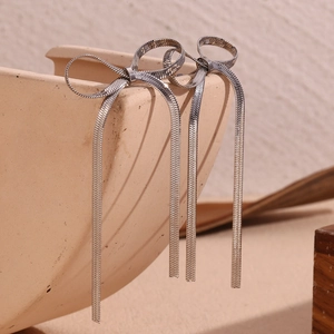 Detail shot of silver bow knot tassel earrings with sleek metal snake chain fringe