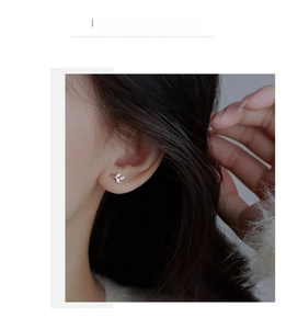 Close-up of S999 sterling silver leaf stud earrings with sparkling white zircons on ear