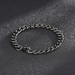 Macro view of vintage stainless steel Cuban link bracelet with lobster clasp on black background
