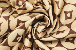 Macro shot of smooth coffee and gold silk fabric with elegant draped spiral texture