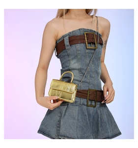 Close-up of gold mini crocodile pattern PU leather bag with metal chain on denim outfit