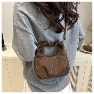 Detail of coffee brown ruched cloud handbag with pleated texture and gold zipper closure