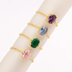 Detail of four colorful oval zircon chain rings in gold, blue, green and pink stones