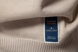 Gros plan de la maille fine beige et de l'étiquette tissée tendance bleu foncé