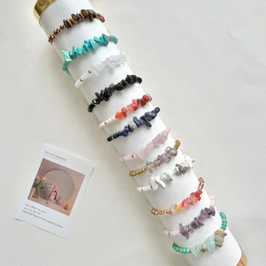 Set of 12 colorful natural gemstone chip beaded bracelets displayed on a white stand
