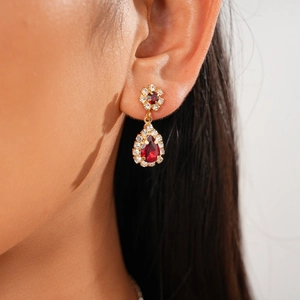 Detail of red teardrop gemstone earrings with gold plating and sparkling crystal accents