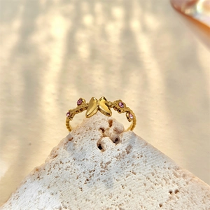 Close-up of a butterfly and flower gold ring on a white stone with natural shadows
