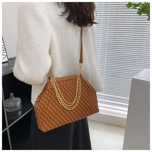 Brown pleated crossbody bag with gold chain strap worn over a white coat in a home setting