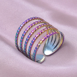 Macro shot of 5-layer rainbow stainless steel open ring on pink silk fabric background