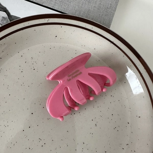 Detailed top view of pink oval hair claw clip with gold engraving on ceramic plate