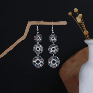 Detailed close-up of Bohemian triple-ring earrings hanging on a natural wood branch