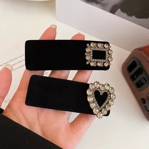 Detail of two vintage black velvet hair clips with heart and rectangle rhinestone accents