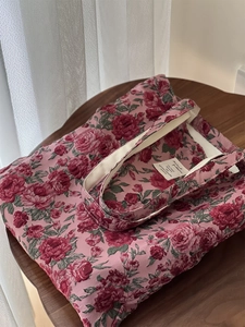 Détail du tissu jacquard à roses roses sur un sac cabas avec étiquette de slogan blanc