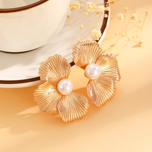 Close-up of golden ginkgo leaf earrings featuring elegant white pearls and radial textures