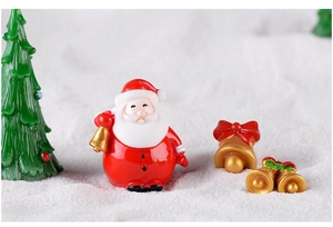 Miniature resin Santa Claus and golden bells on faux snow for holiday decor