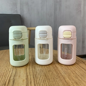 Portable glass coffee mugs with straw in green, white, and pink on a wooden table