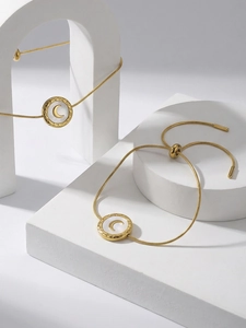 Detail of gold snake chain bracelet with white shell moon pendant and adjustable sliding clasp