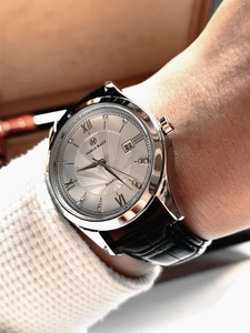 Close-up of quartz men's watch with silver case, Roman numerals and black leather strap