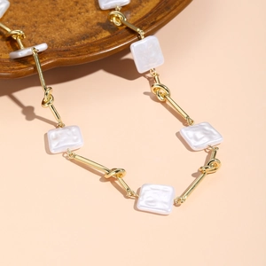 Detailed shot of golden tube links and square resin charms on a baroque style necklace