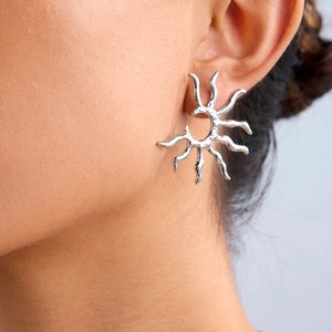 Close-up of a silver irregular sun-shaped earring worn by a model in a macro view
