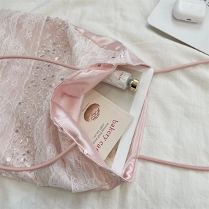 Gros plan du sac en satin rose avec dentelle florale et détails pailletés brillants