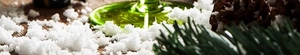 Macro view of green glass base with pine cones and snow for Christmas decor