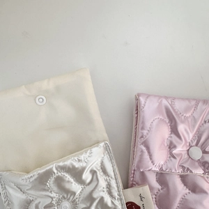 Detailed view of quilted heart pattern satin pouches in pearl white and soft pink