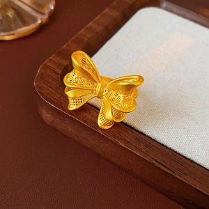 Macro shot of gold bow ring with brushed metal texture on a wooden and linen display