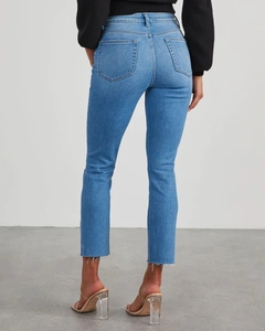 Detail view of high waist blue slim fit jeans with frayed hem on the back side ankle
