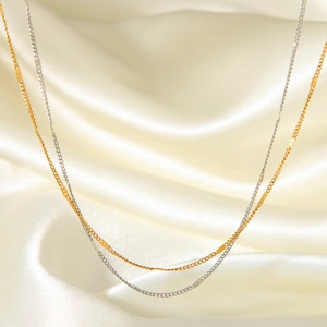 Detail of gold and silver dainty necklaces with metal bars on soft silk fabric