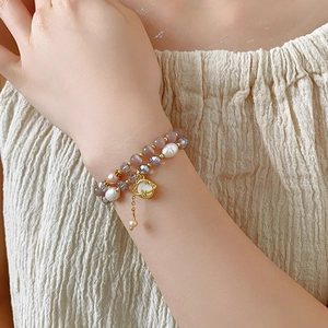 Détail du bracelet double couche en perles avec pendentif planète dorée au poignet