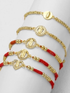 Macro view of five red woven religious bracelets with 18k gold heart pendants and zircons