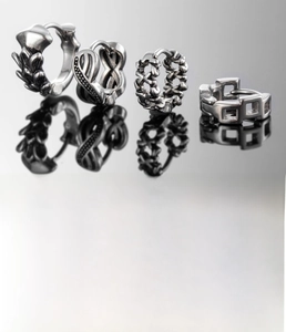 Macro detail of vintage stainless steel hoop earrings with engraved floral and cross patterns