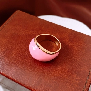 Dettaglio anello tondo dorato smaltato rosa su una scatola di gioielli in pelle marrone