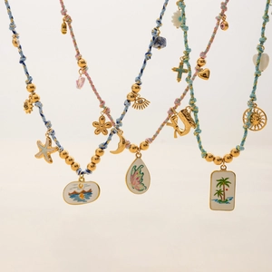 Close-up of three colorful woven necklaces with gold bohemian enamel charms and pendants