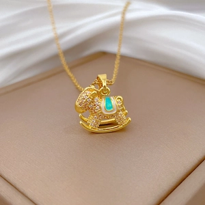 Detailed macro of golden rocking horse necklace with sparkling white zircons and green enamel