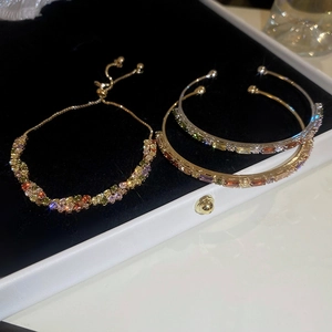 Detailed set of golden bracelets with vibrant multi-color zircon stones on black velvet