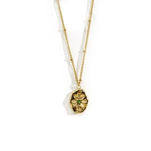 Close-up of gold station chain with oval pendant featuring a star-engraved green gem