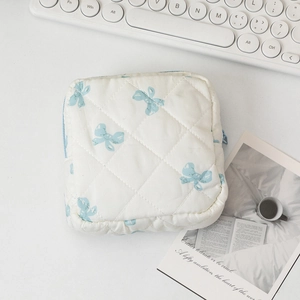 Flat lay of cream quilted toiletry bag with light blue bow patterns on a desk