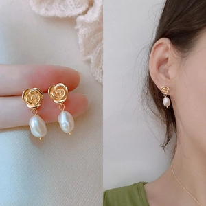 Elegant gold rose stud earrings with white freshwater pearls shown on model and detail